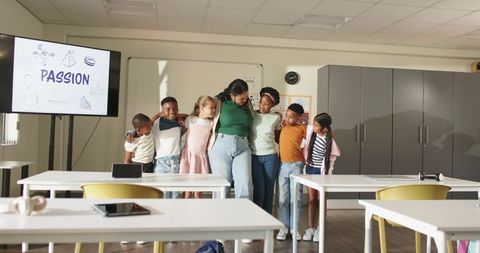 African American teacher hugging diverse students with PASSION slide in classroom