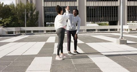 Young couple high-fiving on urban rooftop terrace in casual activewear