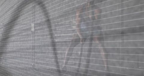 Athlete training with battle ropes behind metal shutter silhouette moody urban gym