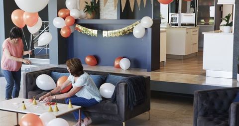 Senior female friends preparing for birthday party with balloons