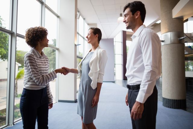Business executives shaking hands in a modern conference center, symbolizing successful partnership and collaboration. Ideal for use in corporate presentations, business websites, networking event promotions, and professional development materials.