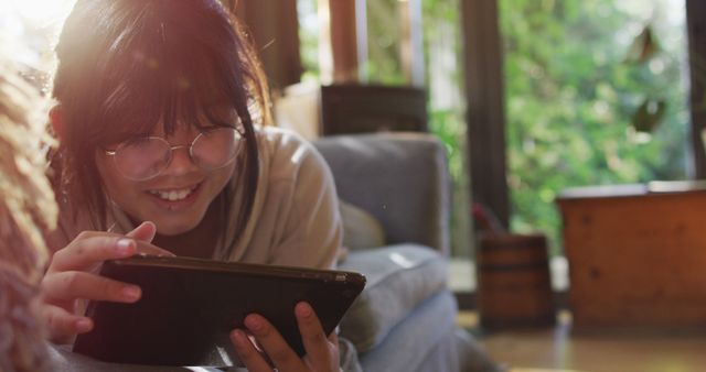 Asian girl lying on couch and using tablet smiling - Download Free Stock Photos Pikwizard.com
