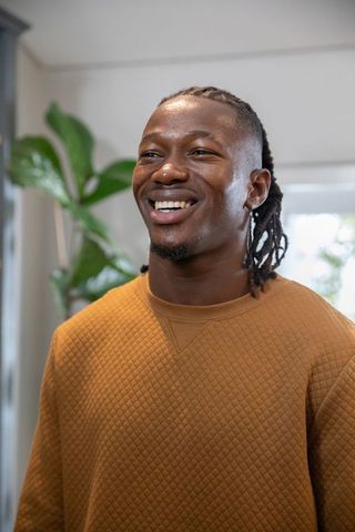 Smiling african american man in bright room with plant background