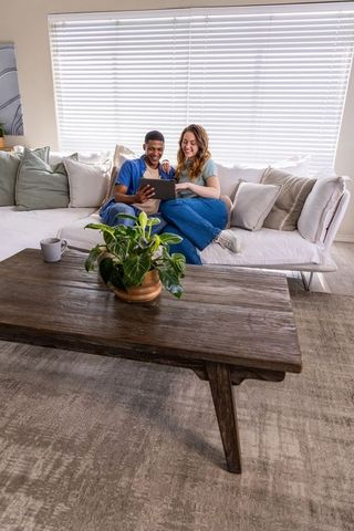 Couple relaxing on white sofa sharing tablet in cozy neutral living room interior