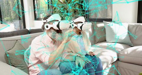 Senior couple wearing VR headsets experiencing virtual reality together on sofa