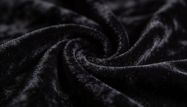 Black velvet spiral swirl showing short-pile sheen and plush folds for luxury backdrops