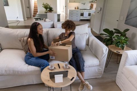 African american friends unboxing package on light sofa in modern minimalist living room
