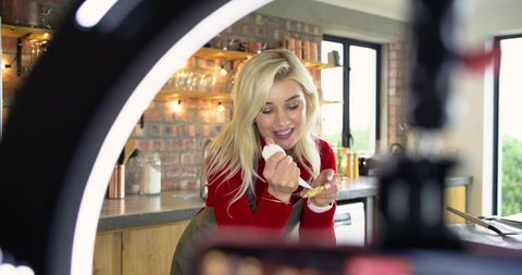 Home cook content creator filming kitchen tutorial with ring light spreading sauce on toast