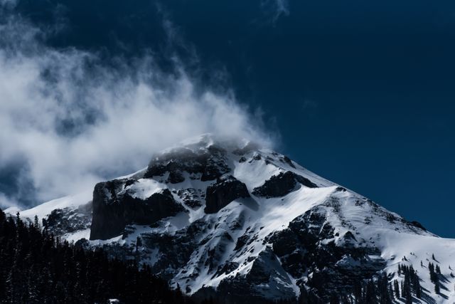 Beautiful snow-capped mountain peak with a cloudy sky perfect for depicting an adventurous and breathtaking natural landscape. Ideal for travel blogs, outdoor adventure marketing, environmental conservation campaigns, wallpapers and scenic calendars.
