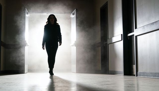 Backlit woman walking through foggy corridor doorway cinematic silhouette dramatic moody