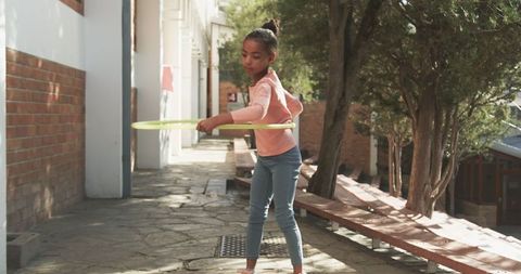 Girl Balancing with Hula Hoop on Sunlit Path