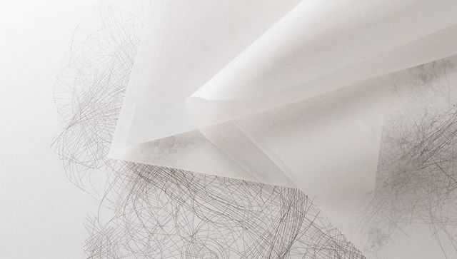 Translucent tracing vellum folding over graphite scribbles, layered pencil texture studio