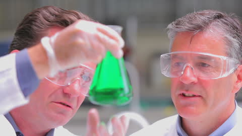 Scientists Analyzing Green Liquid Sample in Lab