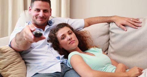 Happy Couple Relaxing on Sofa Watching TV Together at Home