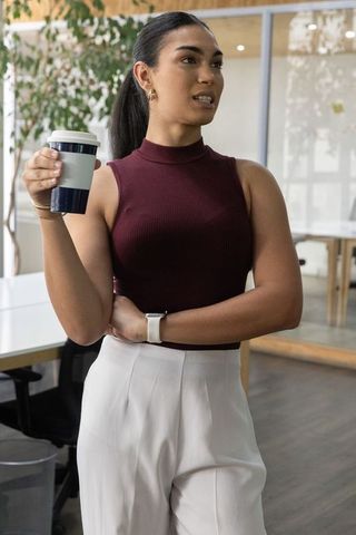 Young professional holding reusable travel coffee cup in bright modern coworking office