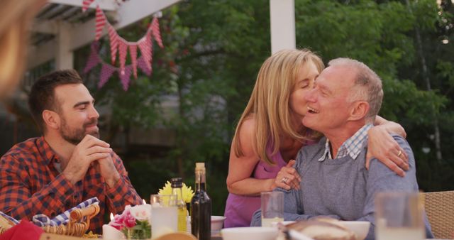 Happy caucasian grandparents embracing and kissing at family dinner table in garden - Download Free Stock Photos Pikwizard.com