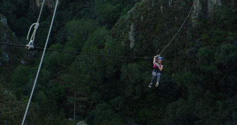 Woman zip lining in scenic mountain landscape