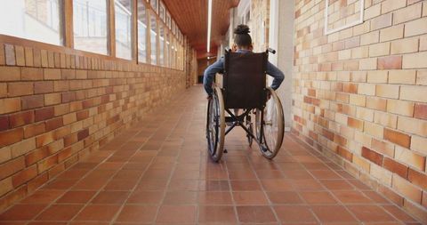 School-age girl maneuvering wheelchair in bright corridor