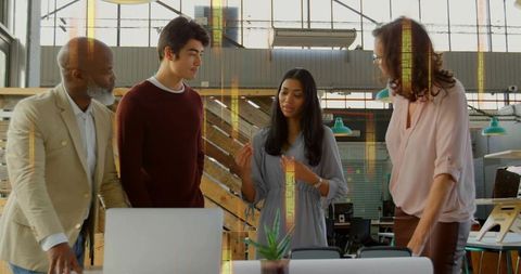 Female leader presenting idea during team brainstorming in modern open-plan office with laptop