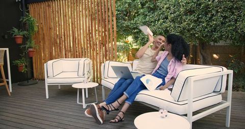 Diverse Couple Relaxing with Laptop in Tranquil Outdoor Garden