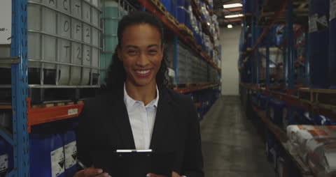 Warehouse Manager Smiling with Clipboard in Storage Aisle