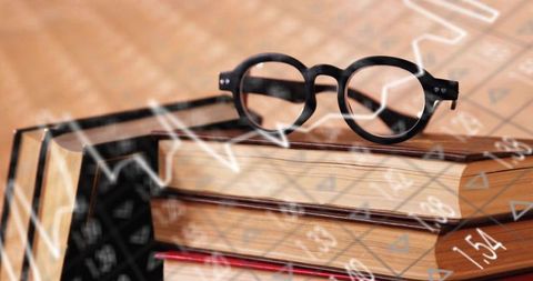 Vintage eyeglasses resting on stacked hardcover books with numeric overlay and warm tones