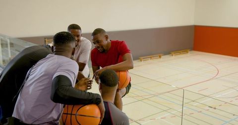 Male players leaning on glass railing planning basketball strategy on indoor court