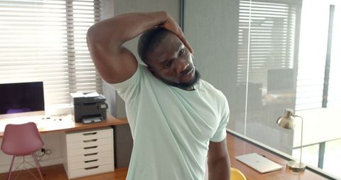 African American Man Stretching Neck in Office Workspace