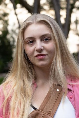Teen blonde woman wearing pink jacket and leather bag outdoor portrait in park