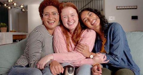 Diverse young women enjoying time together on sofa in stylish home