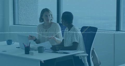 Two Professional Women Collaborating at Workspace Desk