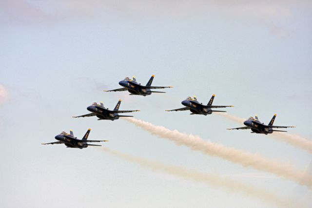 Aerial view of Blue Angels demonstrating tight flight maneuvers in blue sky during Kennedy Space Center Visitor Complex Space and Air Show, in Florida. Event features military aircraft like F/A-18 Super Hornet, precision pilots, veteran astronauts, and a water rescue demonstration by the 920th Rescue Wing. Ideal for use in articles on air shows, military aviation, and space and aviation celebrations.