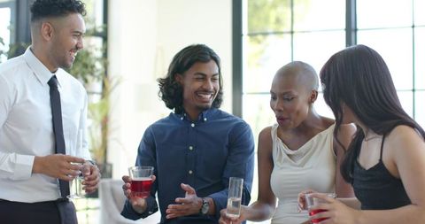 Multicultural friends mingling and enjoying drinks at sunlit cocktail reception