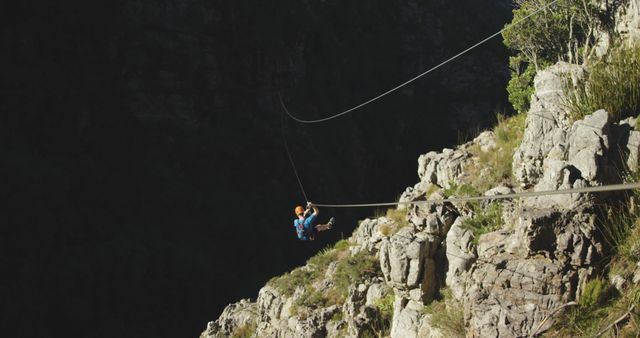 Caucasian man ziplining with safety belts in mountains, copy space. Ziplining, active lifestyle, safety and nature concept, unaltered.