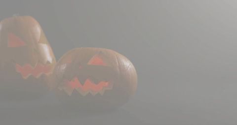 Glowing carved pumpkins casting warm orange light in foggy studio with copy space