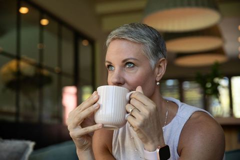 Middle-Aged Woman Sipping from Mug in Cozy Cafe Setting