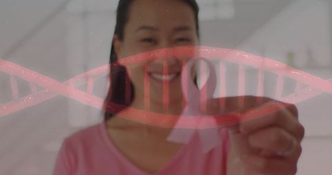 Korean woman holding pink ribbon with dna helix overlay for breast cancer genetics and biotech