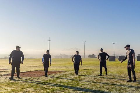 Male Team Practicing Morning Conditioning Drills on Frosty Sports Field at Dawn