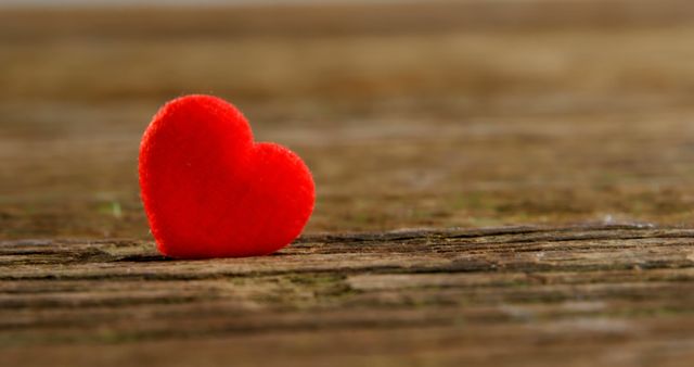A small red heart rests on a textured wooden surface, symbolizing love and affection - Download Free Stock Photos Pikwizard.com