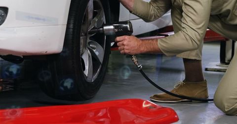 Mechanic Removing Lug Nuts with Air Wrench on Alloy Wheel for Tire Service