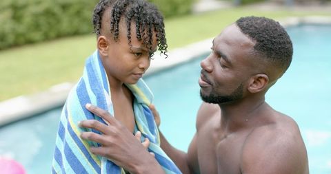 Father Wraps Towel Around Son by Poolside