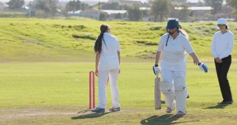Diverse Female Cricketers Playing on Sunny Field with Gear