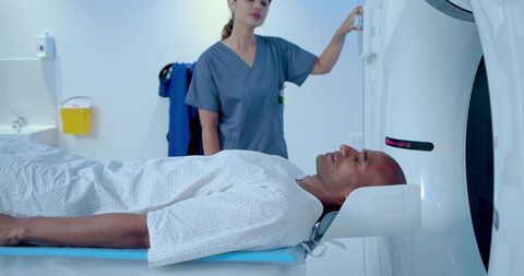 Male patient undergoing ct head scan with laser alignment while technologist operating gantry