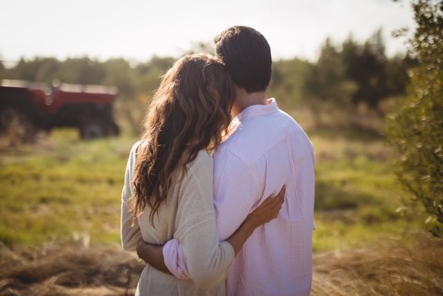 This image captures a young couple embracing in an olive farm on a sunny day, showcasing love and togetherness in a natural setting. Ideal for use in romantic, lifestyle, or nature-themed projects, advertisements, and social media posts promoting relationships, outdoor activities, or rural living.