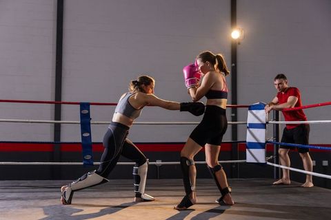 Female boxers sparring in ring throwing jab during intense gym training session
