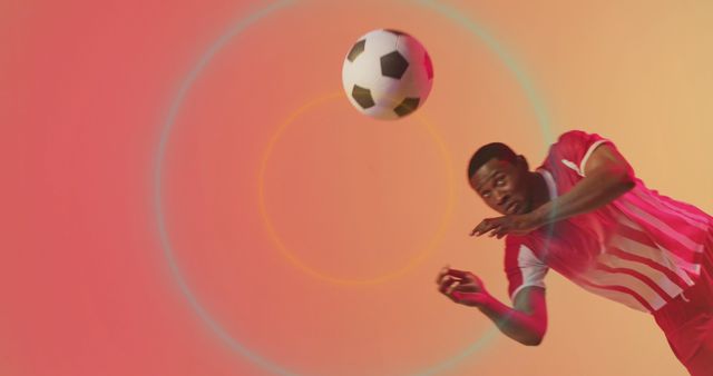 Image shows dynamic capture of a soccer player heading a ball with colorful studio lighting. Great for use in sports promotion, fitness articles, advertising athletic wear, or inspiring an active lifestyle.