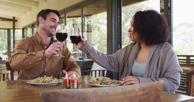 Biracial couple toasting and drinking wine while having lunch at a restaurant - Download Free Stock Photos Pikwizard.com