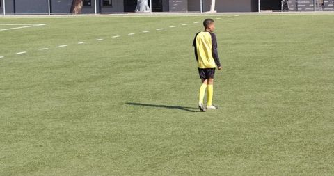 Youth soccer player walking on field with green grass