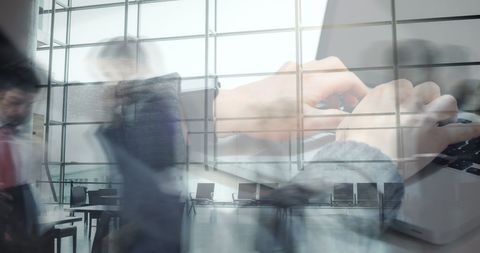 Hands typing on laptop oversets fast-paced office environment