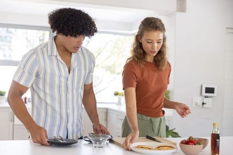 Couple preparing pancakes at bright modern kitchen island, casual weekend breakfast